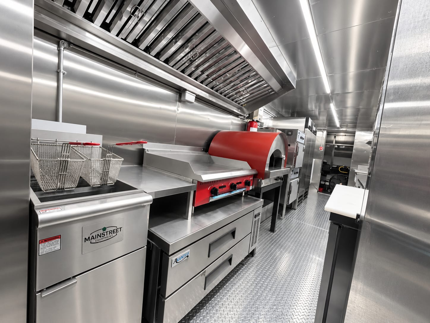 Stainless steel food truck interior with hood, fryer, griddle and prep counters